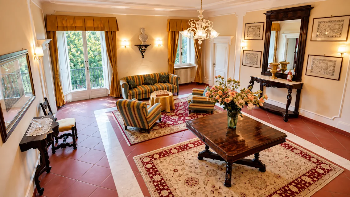 Elegant living room at Villa Vianci, a historic luxury villa in Tuscany near Monteriggioni, with antique furniture and garden views.
